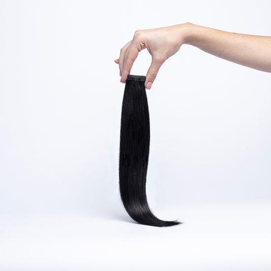 Einzelne chaarmant Classic Tape In Extension in Schwarz, 40 cm, freigestellt in der Hand gehalten