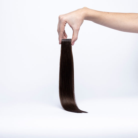 Einzelne chaarmant Classic Tape In Extension in Schwarzbraun, 40 cm, freigestellt in der Hand gehalten
