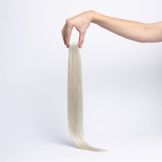 Einzelne chaarmant Classic Tape In Extension in Silber, 55 cm, freigestellt in der Hand gehalten
